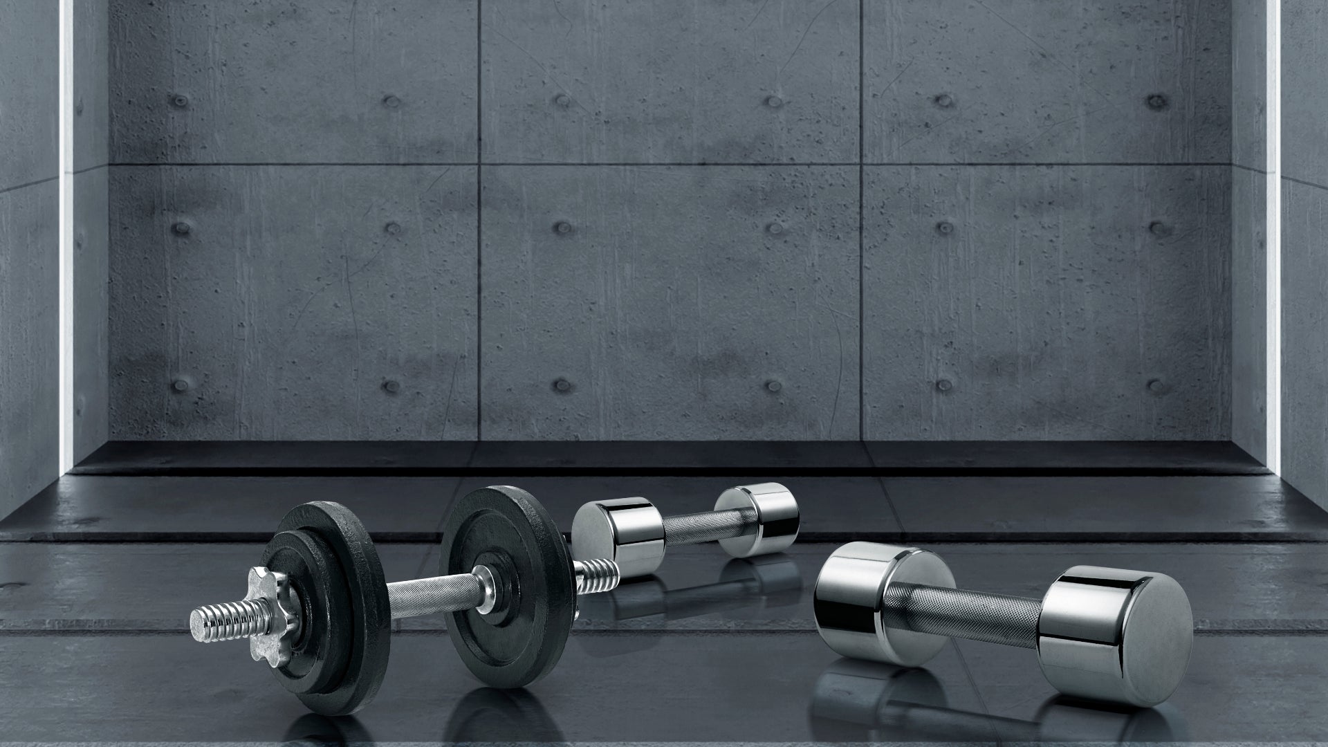Pair of dumbbells on a reflective surface with a concrete wall background