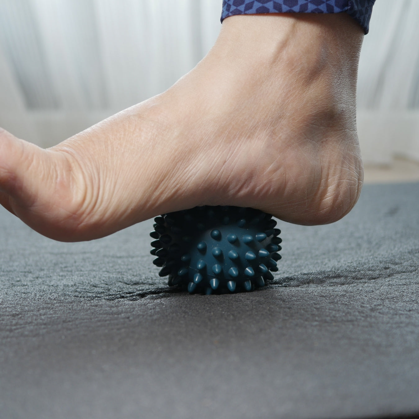 Person using spiky massage ball for foot recovery and muscle relief